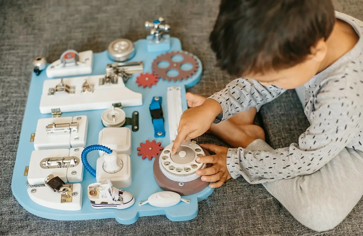 Bébé jouant avec un busy board pour développer la motricité fine et la coordination