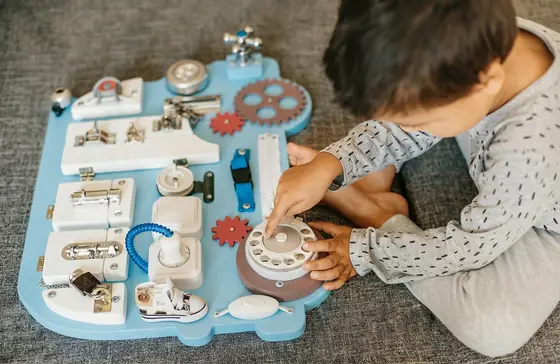 Bébé jouant avec un busy board pour développer la motricité fine et la coordination