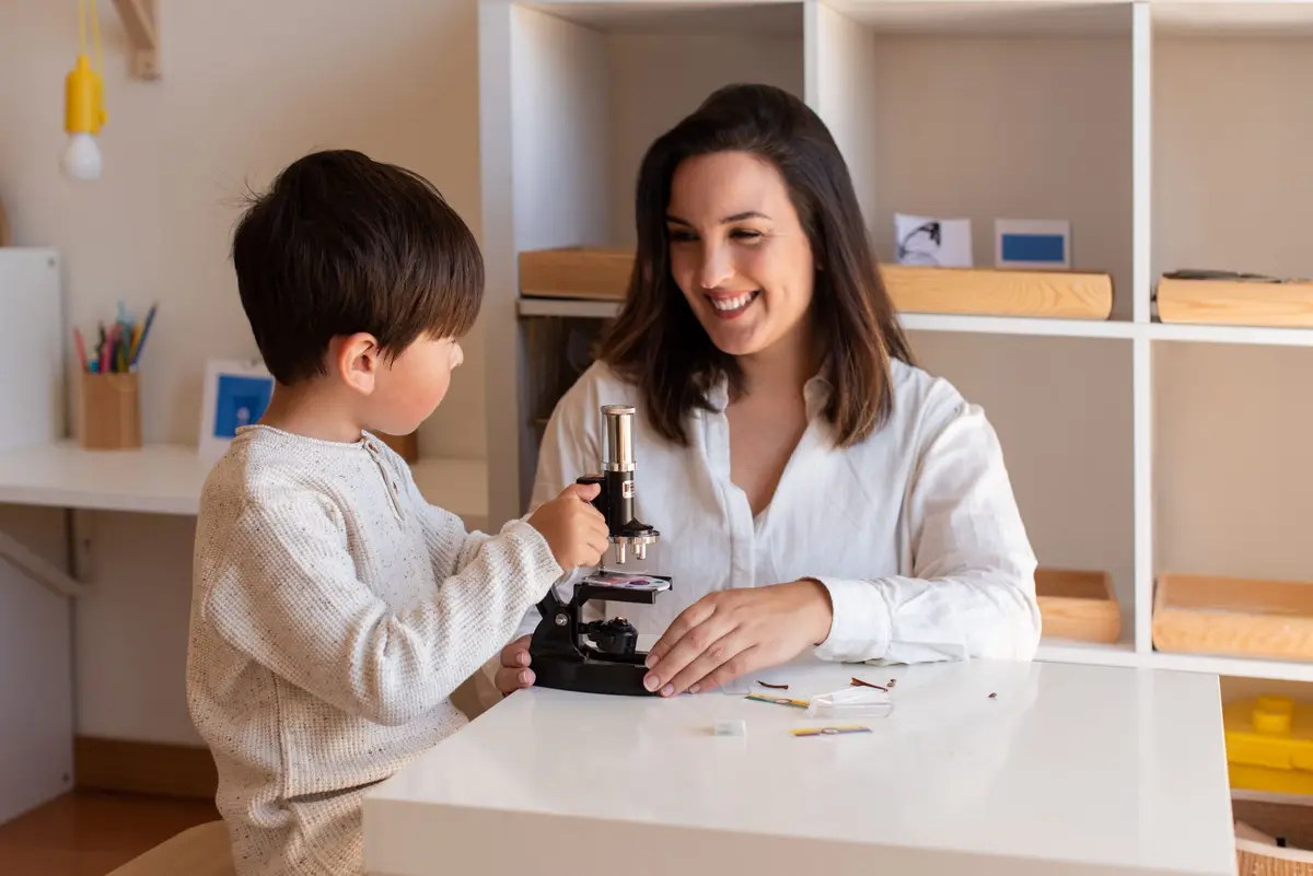 Enfant de 6–12 ans observant une feuille au microscope, accompagné par un adulte